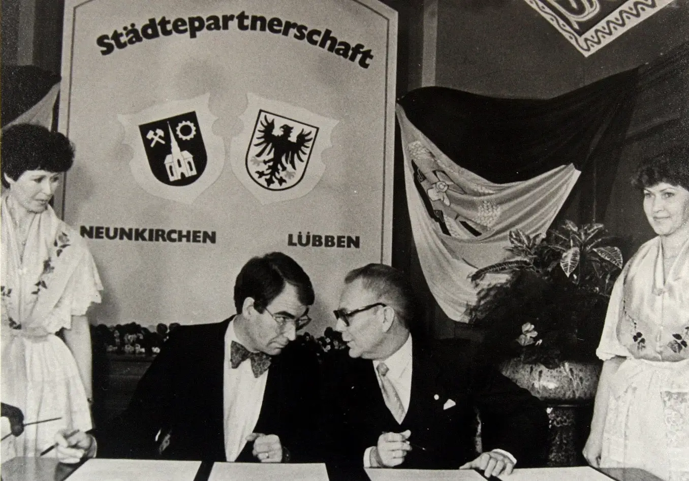 Bei der Unterzeichnung der Städtepartnerschaft zwischen Lübben und Neunkirchen im Wappensaal des Schlosses Lübben stehen Vertreter beider Städte um einen Tisch.